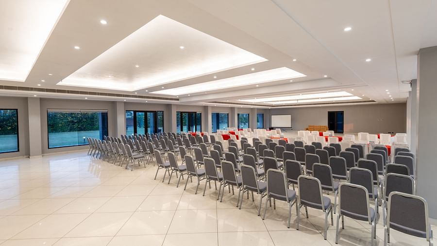 Spacious banquet hall at DLS Forest Vines Resort, with chairs neatly arranged and bright lighting illuminating the space.